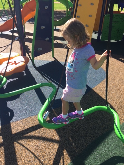 Erin's daughter balancing on the new playground equipment.