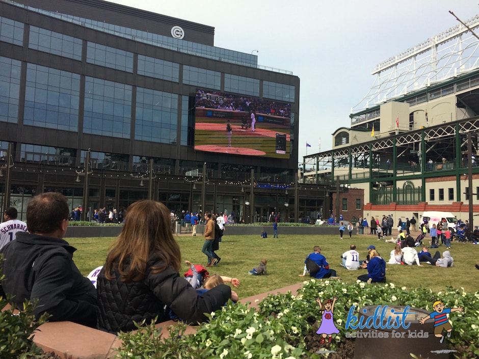 The Park at Wrigley with an open, grassy field and big screen playing the Cubs game