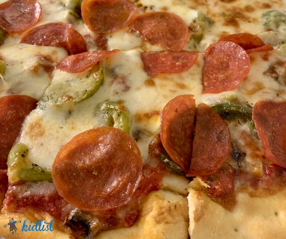 up close picture of a pizza with pepperoni and green bell peppers, showcasign a list of best pizza places