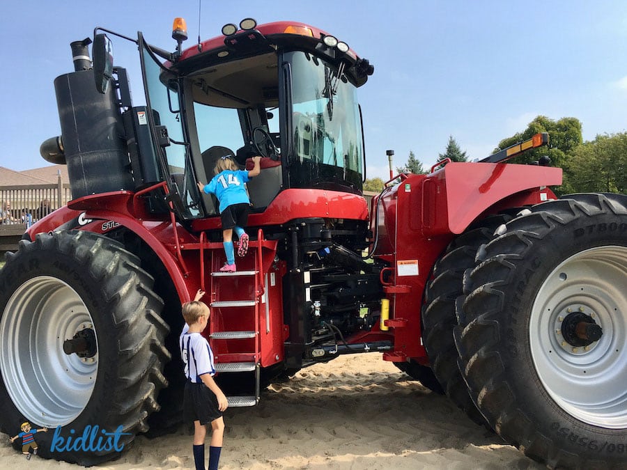 Kids climbing on a bright red tractor at a Touch a Truck event.