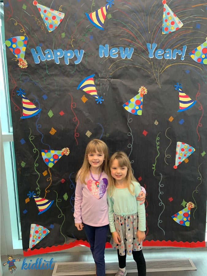 two girls standing in front of a decorated background celebrating noon year's eve