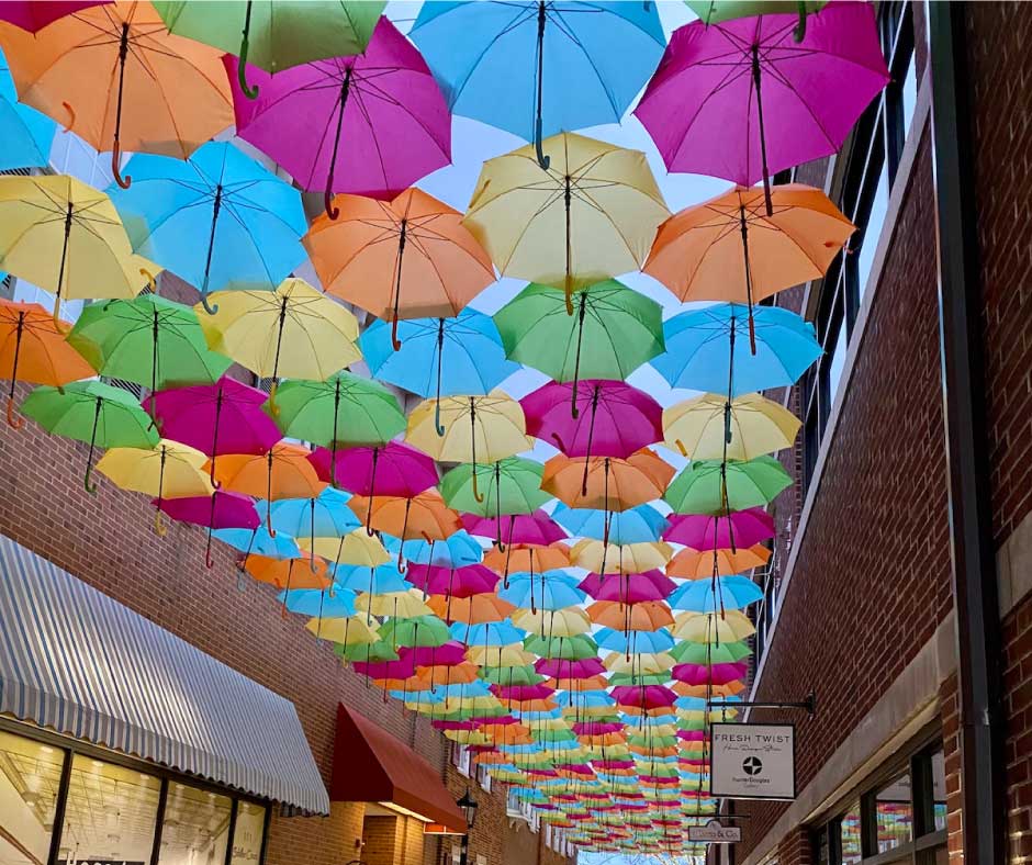 immersive experience with umbrellas hung next to each other over Schiller Court in Elmhurst with light streaming through the fabric