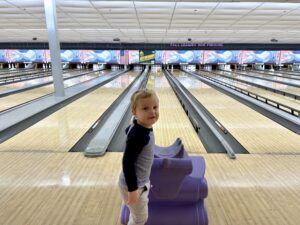 A child stands in front of a bowling lane.