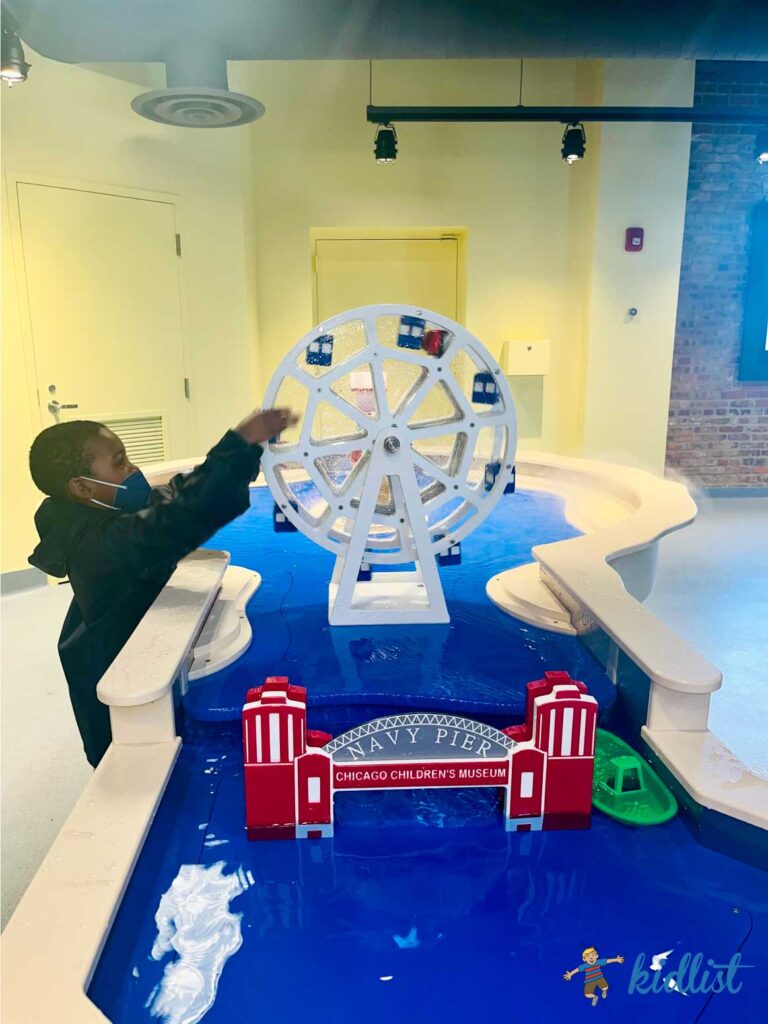 Child spinning a model of the Ferris Wheel at Navy Pier at the Chicago Children's Museum's Water City exhibit.