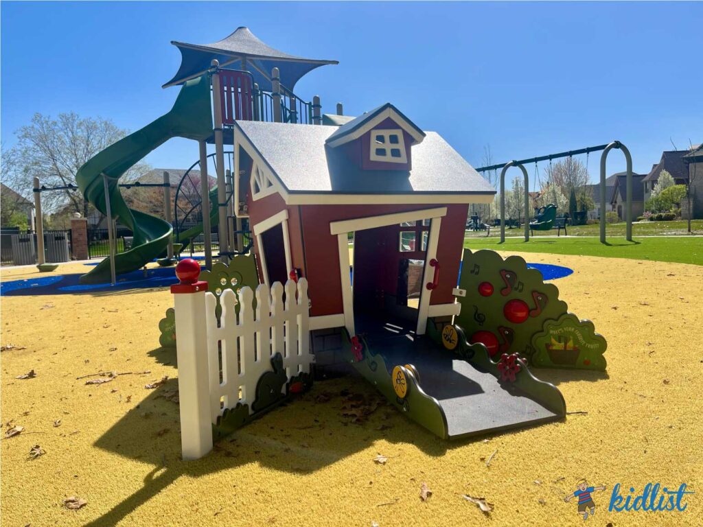 Briarcliffe Park in Lemont, with a spongy turf surface and small play house in front of a larger play structure and swings.