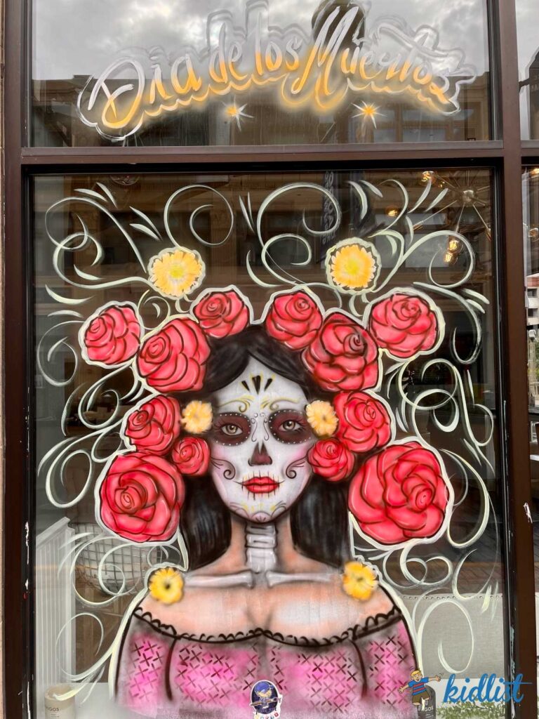A window painted with a mural of a woman with sugar skull face paint.