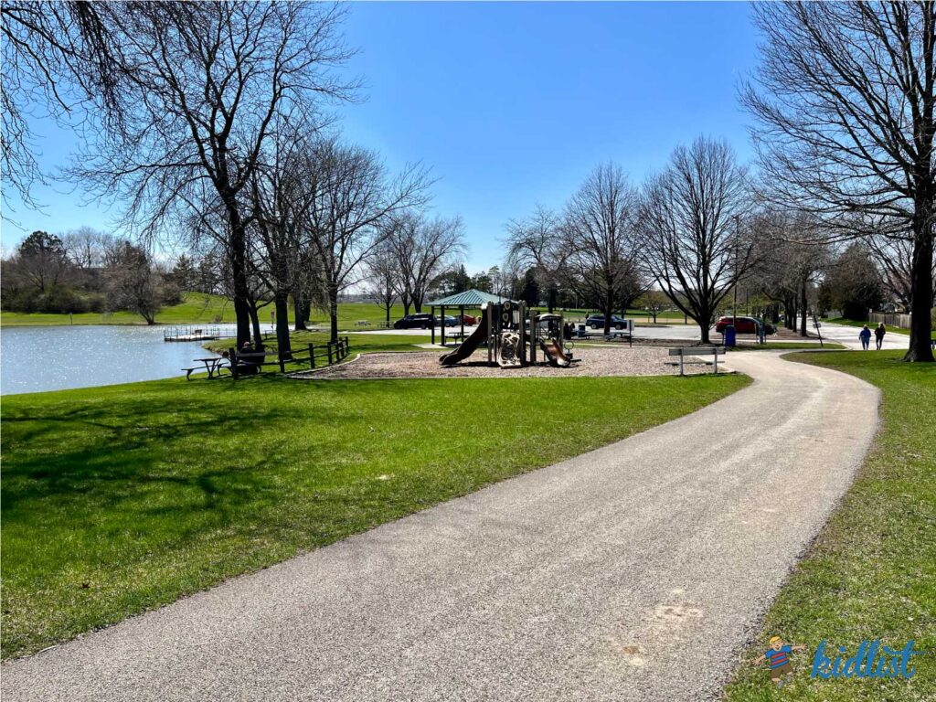 Paved walking path that leads to a lagoon, with benches and a picnic table.
