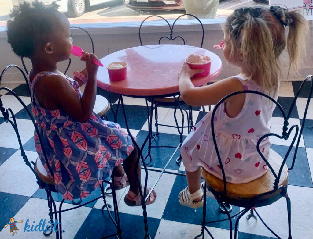 Kids sitting at a table eating ice cream in an ice cream parlor.