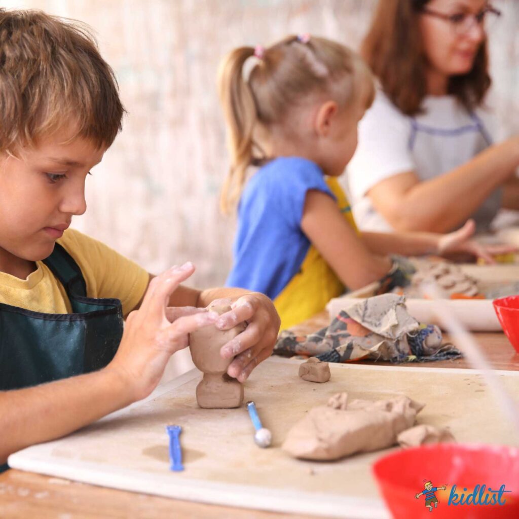 kids pottery classes with a boy in the forefront working with clay