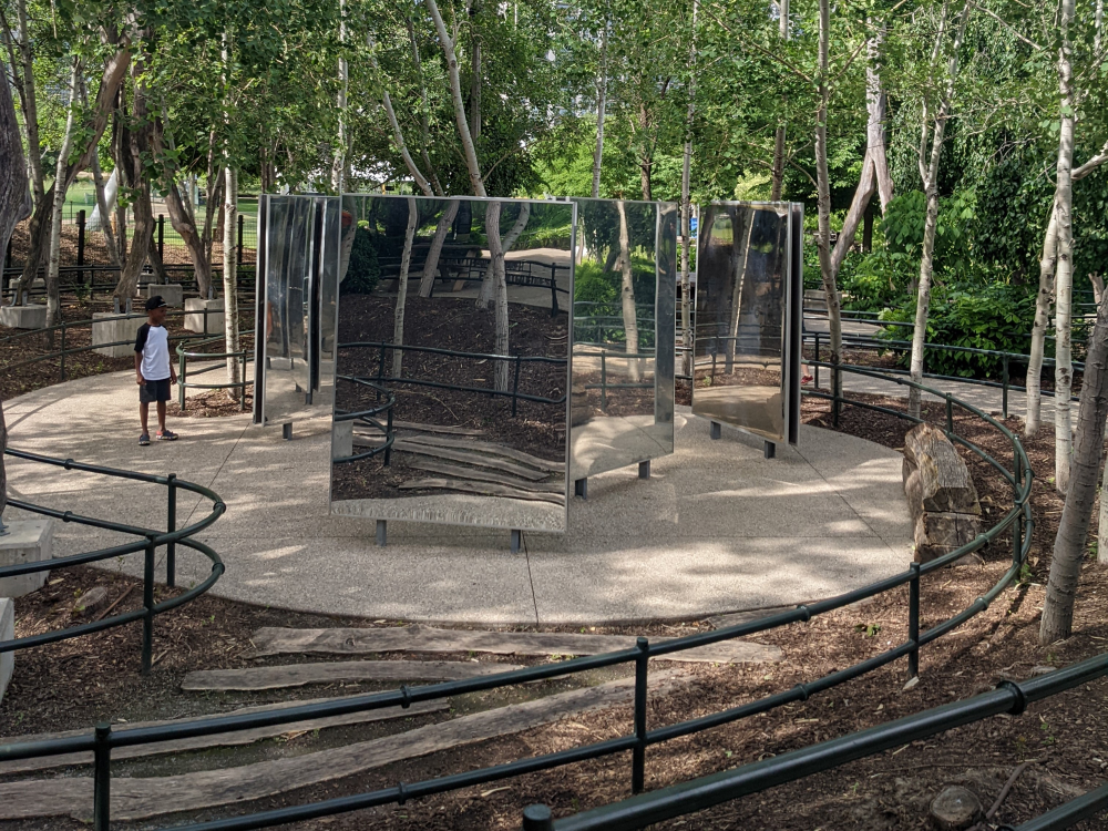 An area with mirrors amidst shady trees at Maggie Daley Park's Play Garden in Chicago.