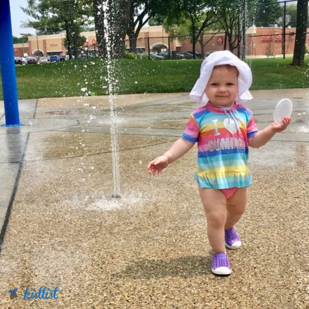 Little girl walking by a water spray at the Memorial Park splash pad in La Grange Park IL