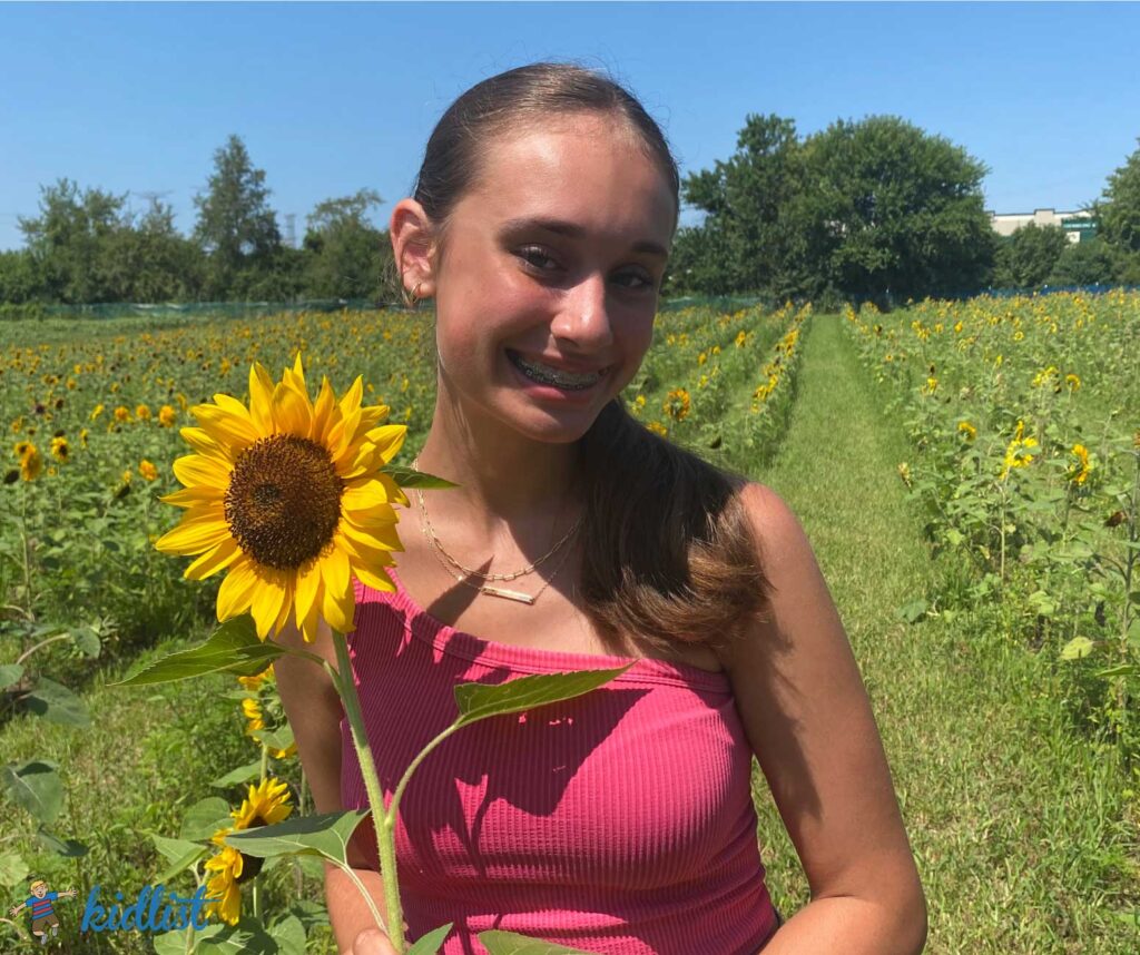 Teenager holding a flower in the middle of a sunflower field