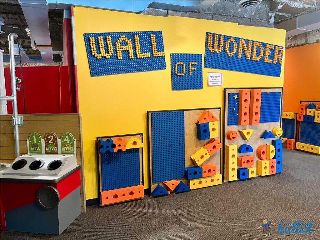 A play wall labeled 'Wall of Wonder' with low play features for young children.